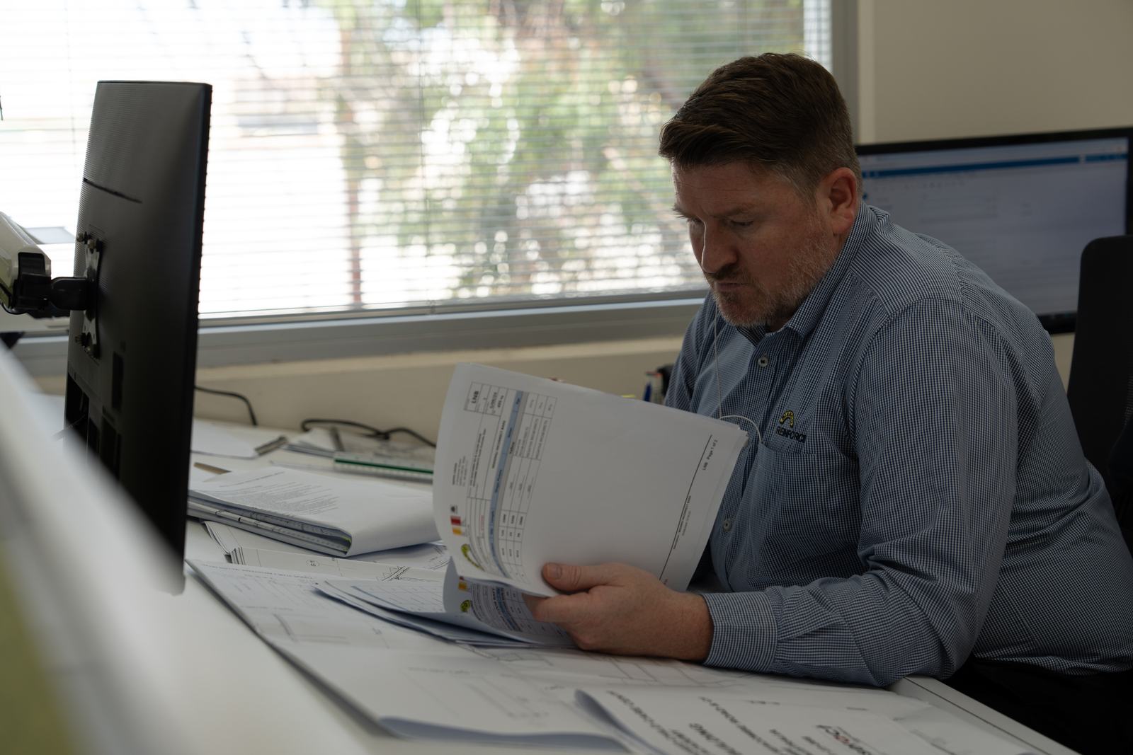 Estimator reviewing printed plans at his desk