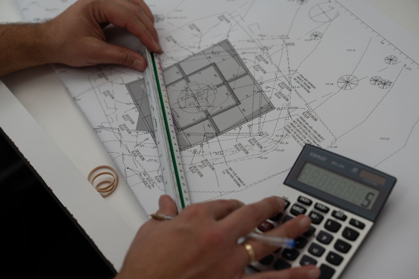 Estimator measuring structural drawings with a scale ruler and calculator